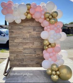 a bunch of balloons that are in front of a wooden wall with a sign on it