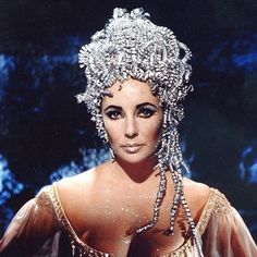 a woman wearing a tiara and dress with pearls on her head is posing for the camera