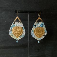 These earrings were made from a vintage tin of blue, white and gold. The findings are brass. The hearts in the center of each earring are raw vintage brass. All marks and scratches are a design element and intentional. Bohemian Gold Earrings With Patina, Gold Bohemian Earrings With Patina, Vintage Blue Brass Earrings, Artisan Blue Brass Earrings, Gold Earrings With Patina For Gift, Gold Earrings With Patina As A Gift, One Of A Kind Gold Teardrop Earrings, Handmade Gold Earrings For Vintage Collection, Vintage Teardrop Patina Earrings