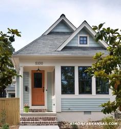 a small blue and white house with a red door