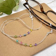 Colorful and bohemian eye glasses necklace chain in crystal clear tones with delicate multicolor flashes and silver notes, featuring small cubic zirconia charms. The necklace is made with Preciosa Czech crystal seed beads, tiny silver plated crystal seed beads and delicate colorful cubic zirconia crystal beads. Paired with tiny, delicate silver plated crystal beads, this handmade eyeglass chain will definitely create a unique look. This eyeglass lanyard is made on strong quality beading wire wit Adjustable Rainbow Glass Necklaces, Adjustable Rainbow Glass Necklace, Rainbow Glass Jewelry For Gifts, Rainbow Glass Jewelry Gift, Adjustable Glass Necklaces With Tiny Beads, Adjustable Glass Necklace With Tiny Beads, White Glass Jewelry For Festivals, White Glass Festival Jewelry, Adjustable Clear Beaded Jewelry