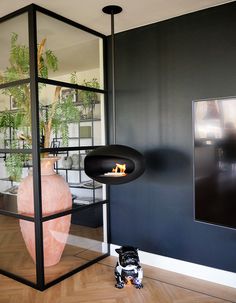 a room with a fireplace in the center and a large vase on the floor next to it