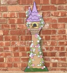 a tall clock with a purple hat on it's face and flowers around the top