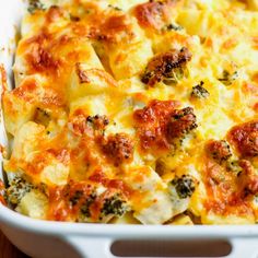 a casserole dish with broccoli, cheese and sauce in it on a wooden table