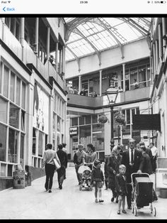 an old black and white photo of people walking through a building with baby strollers