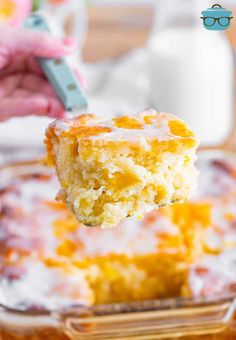 a piece of cake is being lifted from a glass casserole dish with white icing