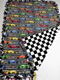 a pile of toy cars sitting on top of a white table next to a black and white checkered flag