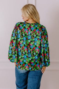 - For a feminine option with luxe vibes add this flowy top to your wardrobe! - Lightweight material with a blue, green, red, and pink hued abstract floral print and a satin finish - A built-in lining - A ruffled v-cut neckline - Long, loose sleeves with elastic cuffs - A relaxed silhouette that ends in a straight hemline Green V-neck Top With Vibrant Print, Vibrant Green Floral Print Blouse, Vibrant Green Long Sleeve Blouse, Vibrant Green Spring Tops, Chic Green Blouse With Abstract Print, Green Floral Print Fall Tops, Green Floral Print Tops For Fall, Green Abstract Print Tops For Fall, Green Blouse With Vibrant Print