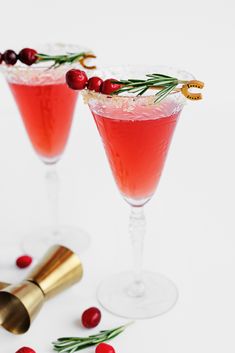 two glasses filled with cranberry and rosemary spritkle cocktails on a white surface