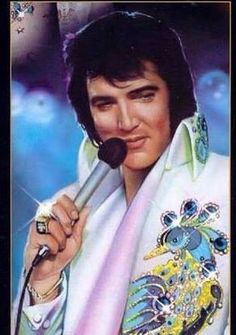 elvis presley holding a microphone in his right hand and wearing a white jacket with blue flowers on it