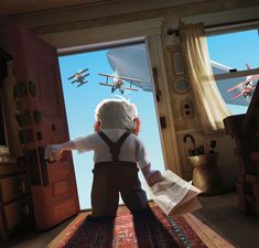 a little boy standing in front of an open door looking out at airplanes flying overhead