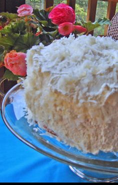 a close up of a cake on a glass plate with flowers in the back ground