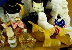 various glass figurines are sitting on a wooden table next to bottles and jars