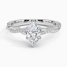 a white gold engagement ring with a pear shaped center stone and pave set shoulders