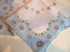 two blue and white handkerchiefs with pink flowers on them sitting next to each other