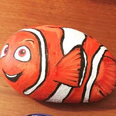 an orange and white fish painted on top of a rock