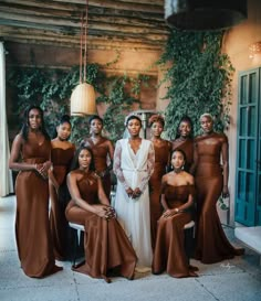 a group of women standing next to each other in brown dresses and one woman wearing a white dress