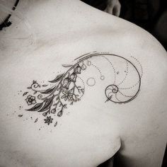 a woman's back tattoo with flowers and swirls