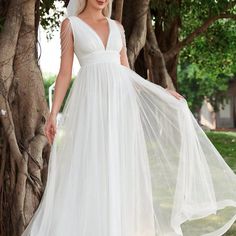 a woman in a white wedding dress standing next to a tree and wearing a veil