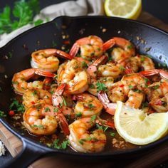 cooked shrimp in a skillet with lemon wedges and parsley on the side