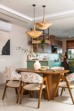 a dining room table with four chairs and a vase on top of it in front of a kitchen