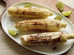 grilled corn on the cob with limes and seasoning next to it