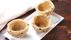 three chocolate chip cookie cups on a white plate with coffee beans scattered around the edges