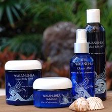 three bottles of body care products sitting on a wooden table next to a seashell