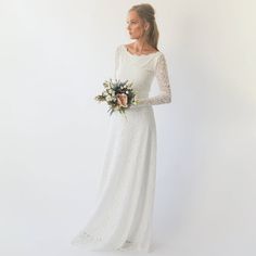 a woman in a long white dress holding a bouquet and looking off to the side