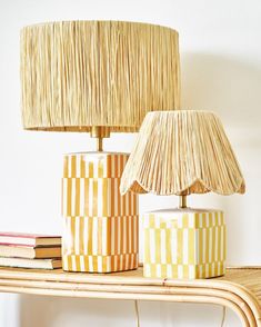 two lamps sitting on top of a wooden table next to a lamp with a shade