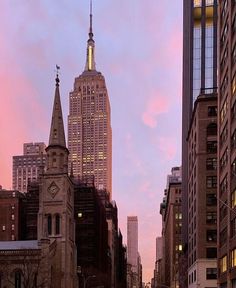 a city street filled with traffic and tall buildings in the background at sunset or dawn