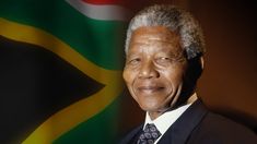 an older man wearing a suit and tie standing in front of a south african flag