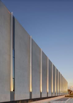 an exterior view of a building with tall concrete walls and lights on the outside wall