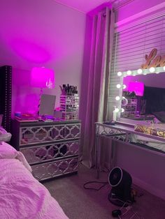 a bedroom with pink lighting and mirrored dressers in the corner, along with other items