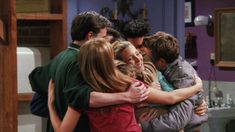 a group of people hugging each other in a kitchen