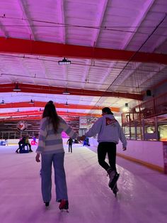 two people skating on an indoor ice rink