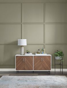 a living room with a rug, table lamp and two sideboards on the wall