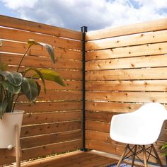 a white chair sitting on top of a wooden deck next to a potted plant