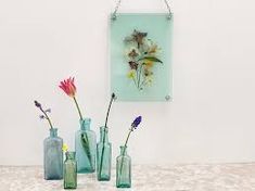 three vases with flowers in them sitting on a table next to a wall hanging