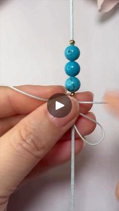 someone is making something with beads on the end of a string and then pulling them apart