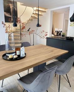 a wooden table topped with gray chairs next to a stair case