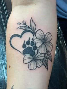 a dog paw and flower tattoo on the left arm, with a heart in the middle