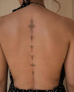 the back of a woman's neck with an intricate tattoo design on her lower back