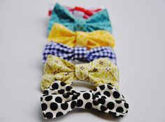 four bow ties are lined up on a white surface, each with different colors and patterns