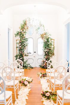 the ceremony room is decorated with white chairs and flowers