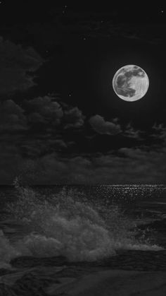 a full moon is seen over the ocean in this black and white photo with waves