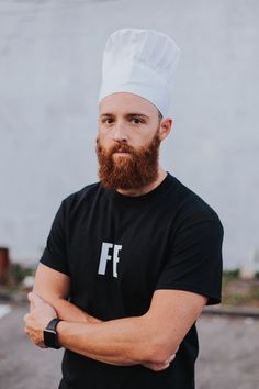 a man with a beard wearing a chef's hat and looking at the camera