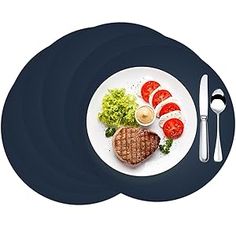 a white plate topped with meat and veggies next to a knife and fork