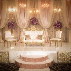 an elaborately decorated stage with white couches and pink flowers