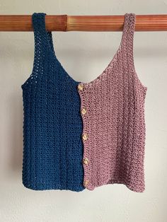 two crocheted tank tops hanging on a wooden rack against a white wall, one in blue and the other in pink